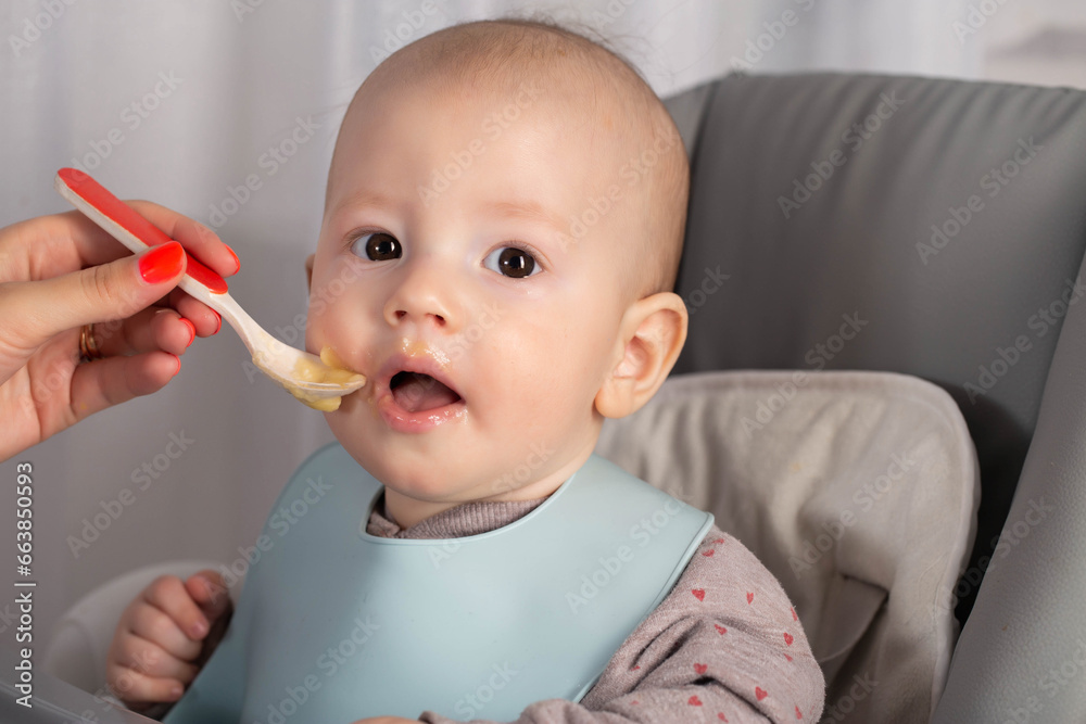 The first feeding with fruit puree for a baby boy who is 6 months old, close-up The first feeding with fruit puree for a baby boy who is 6 months old, close-up