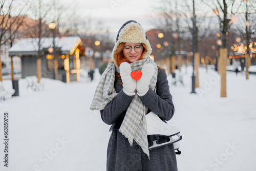 young beautiful woman is holding red card in form of heart, Valentine's day, Valentine's Day. happy woman in life clothes walks in park on date and enjoys life. Winter holidays love freedom