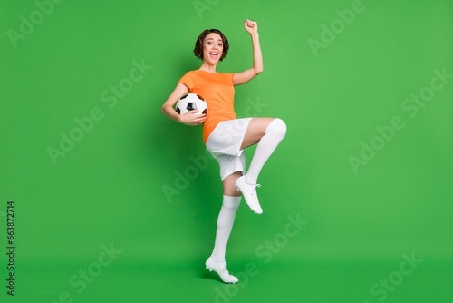 Full length photo of delighted person open mouth fist knee up scream yeah celebrate isolated on green color background
