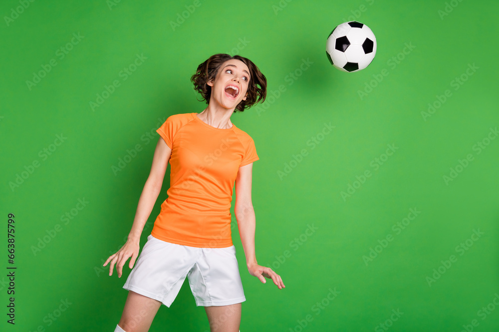 Photo of carefree astonished girl open mouth look flying ball head make shot isolated on green color background Photo of carefree astonished girl open mouth look flying ball head make shot isolated on green color background