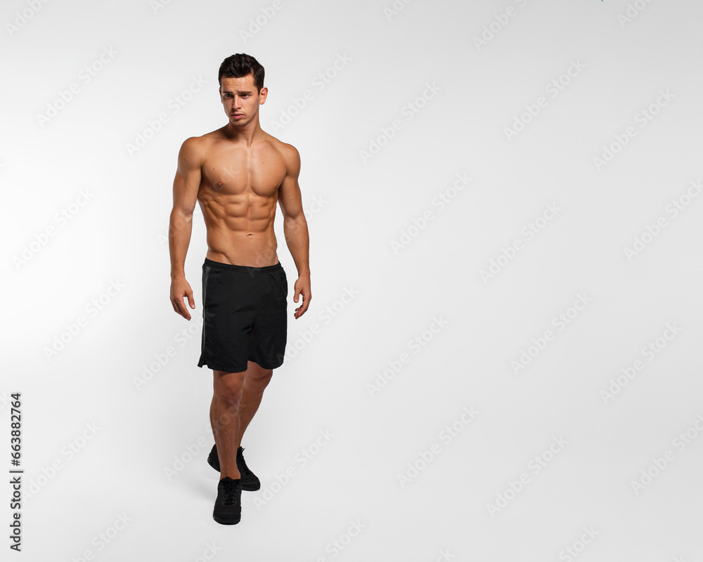 Full length image of a man with an athletic and fit body, posing in the studio with a bare torso, showing six abs pack, isolated on the white background. Full length image of a man with an athletic and fit body, posing in the studio with a bare torso, showing six abs pack, isolated on the white background.