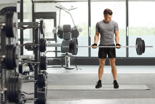Young fit guy lifting weights at a gym © Ljupco Smokovski