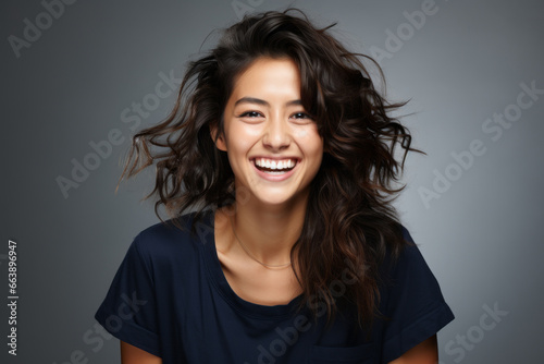 Retrato frontal de mujer joven  sonriente de rasgos asiáticos sobre fondo neutral. Copy space.
