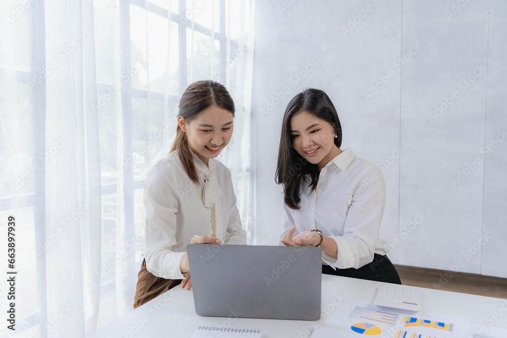 Two Asian businesswomen discuss investment project work and planning strategies on data charts and planning strategies. About new businesses in the online financial world Asian startup business ideas Two Asian businesswomen discuss investment project work and planning strategies on data charts and planning strategies. About new businesses in the online financial world Asian startup business ideas