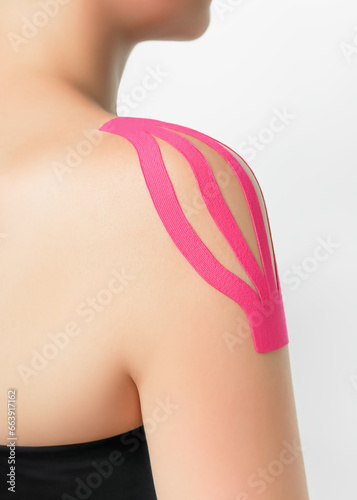 a woman wears pink kinesio tape on her shoulder. kinesio taping of the shoulder to relieve pain in the shoulder joint photo