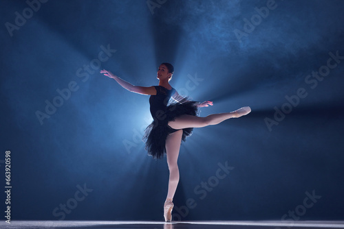 Elegant performance. Beautiful young woman, professional ballet dancer n motion, dancing over blue background with smoke. Concept of classical dance, art and grace, beauty, choreography, inspiration