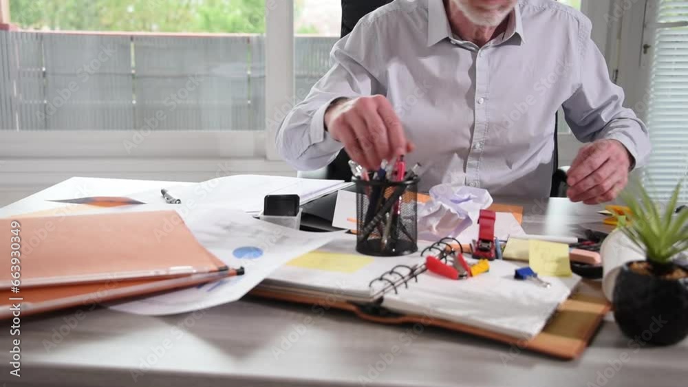 Disorganized businessman working and looking for something on a messy desk Disorganized businessman working and looking for something on a messy desk