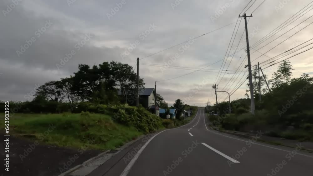 Driving open road by rustic houses on Rishiri Island at golden hour Driving open road by rustic houses on Rishiri Island at golden hour