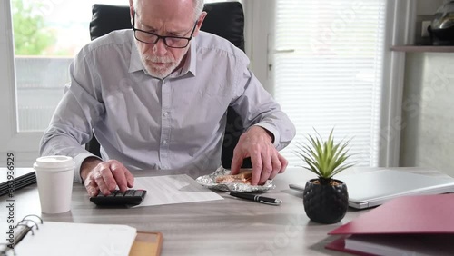 Businessman eating a sandwich while working at office