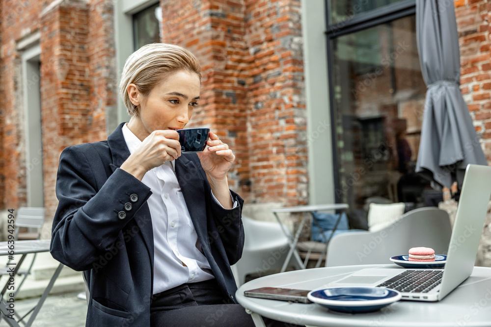 Fototapeta premium Young manager working and having morning coffee in a street cafe