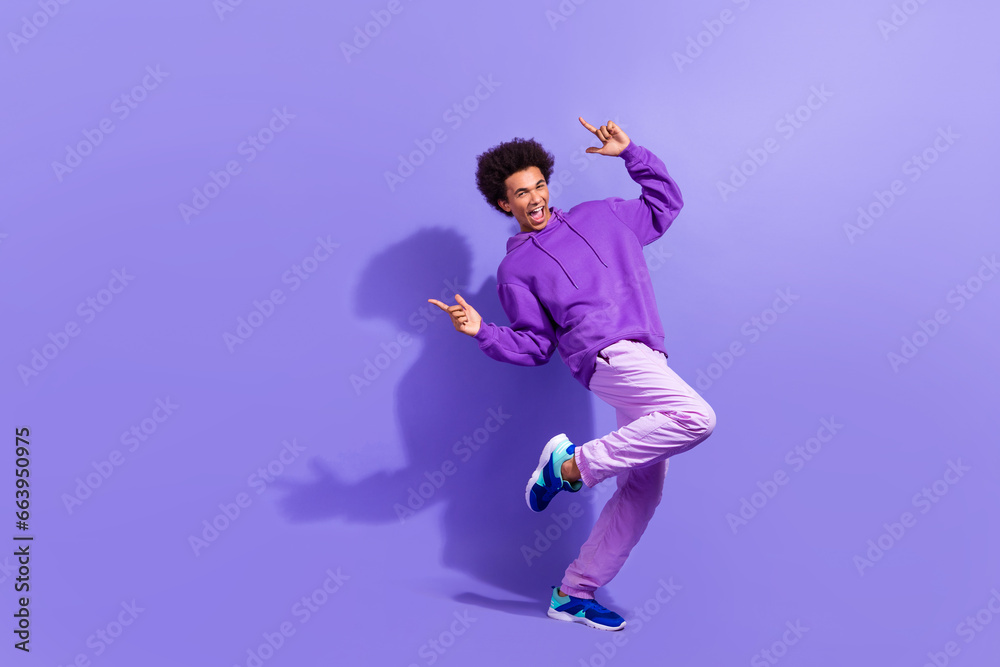 Full length photo of optimistic positive guy afro hairdo dressed purple pullover promoting shopping isolated on violet color background Full length photo of optimistic positive guy afro hairdo dressed purple pullover promoting shopping isolated on violet color background