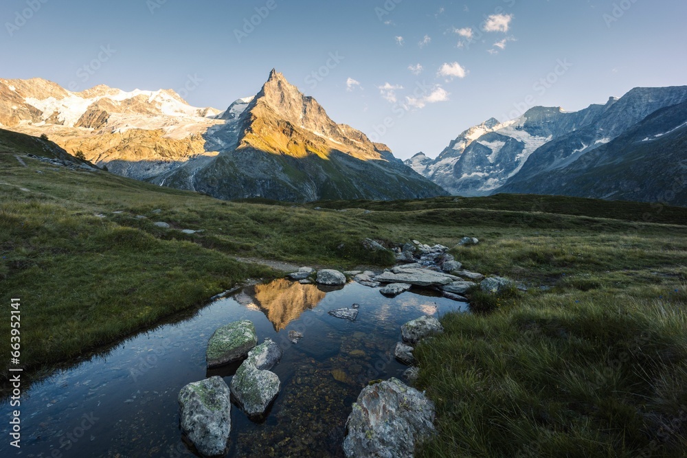 Landscape summer view of a mountain peak reflecting in a stream at sunset