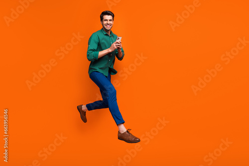 Full body cadre of young funky businessman running with smartphone enjoy shopping no commission estore isolated on orange color background