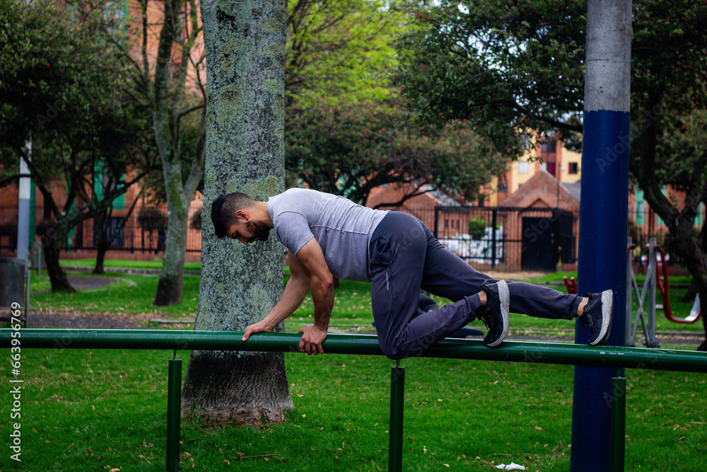 Fototapeta premium young sportsman in sportswear doing front squat on one leg forward with hands folded outside in city park during routine workout in morning
