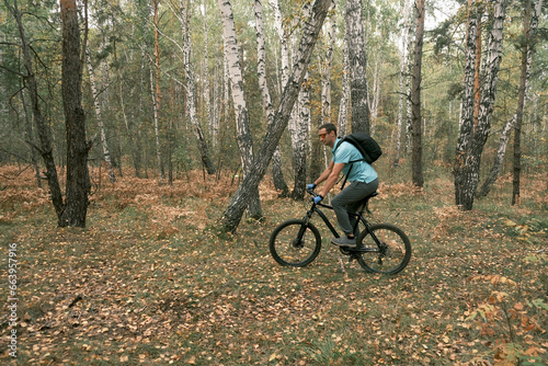  active lifestyle.A cyclist with a backpack rides a black mountain bike through a coniferous forest in autumn.Mountain Bike
