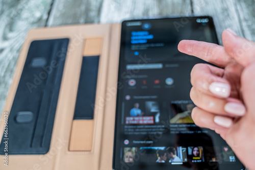 Female hand, tablet turned on. Wooden background.