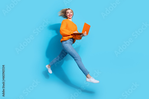 Full length profile photo of energetic cheerful person jump rush use netbook isolated on blue color background