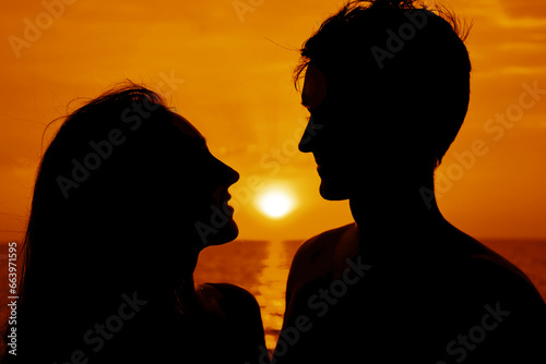 Silhouette of Couple Man and Woman kissing in Love. lovers staying on Beach seaside coast with Sunset sky. Romantic pair in love. relationship, Friendship concept. sun rays between heads. face to face