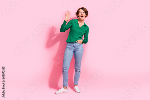 Full body length photo of friendly young lady waving palm combinated to jeans welcome you in store isolated on pink color background photo