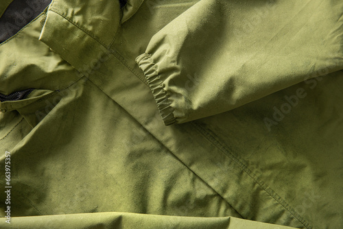 Green waterproof jacket covered with drops of water.