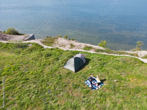 Camping in nature in Estonia in summer. A young couple makes a picnic near a tent on a sea cliff in Paldiski.