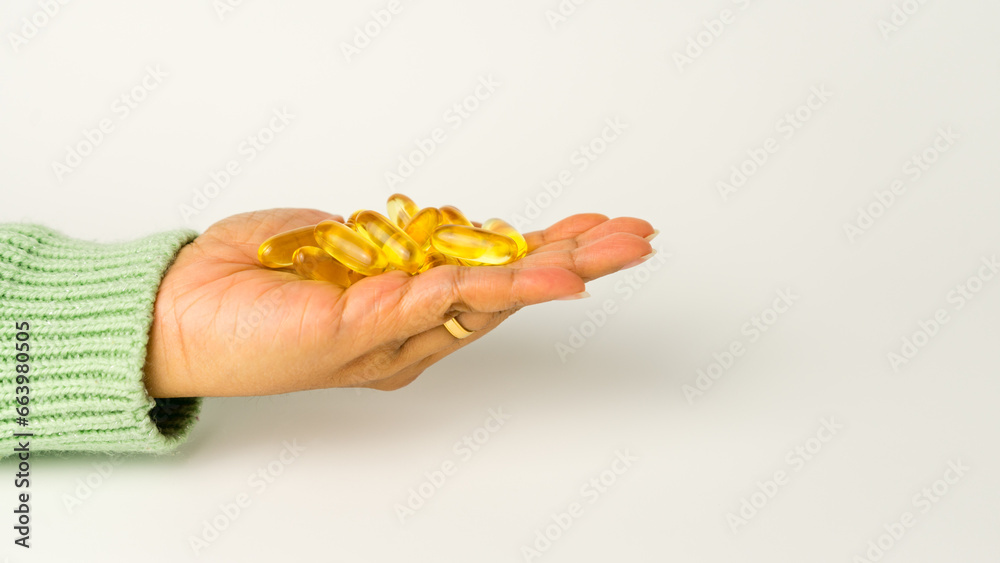 Obraz premium Holding Omega-3-rich wild salmon and fish oil capsules against a gentle off-white background.