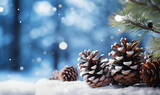 Banner with falling snow and pine branches and pine cones on light blue blurred background, empty space for inserting text or logos, holiday theme