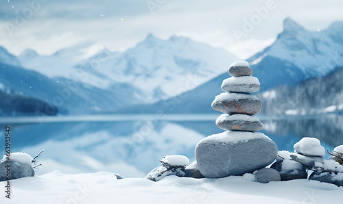 Winter panorama with snow-covered stones on a blanket of white snow in the distance mountains reflected on a frozen lake