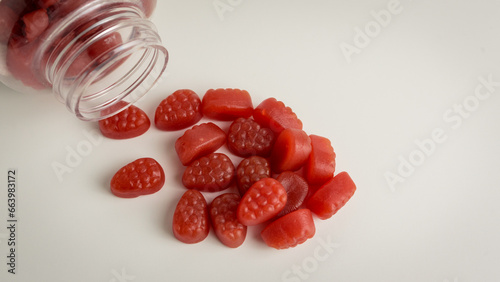 Biotin Gummies for Hair, Skin, and Nails spilling out from the bottle, showcased against a gentle off-white background.