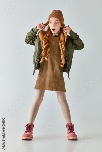 Принти на полотні shocked preteen girl with long hair posing in stylish winter outfit and hat on g