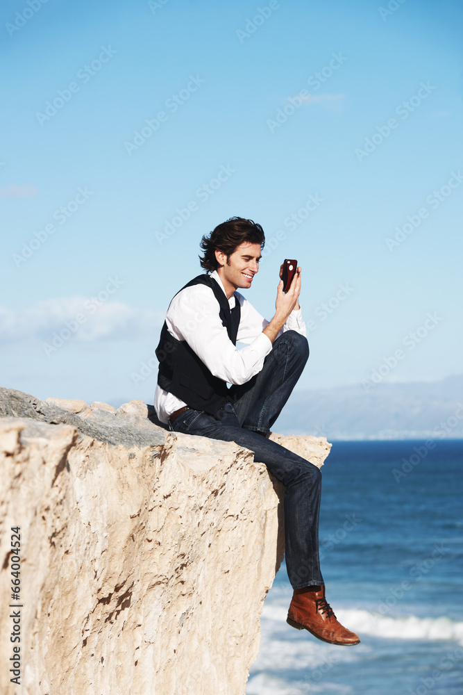 Cliff, edge and man with a phone at the ocean, beach or happy connection on vacation, travel or social media. Businessman, contact and edgy chat with cellphone, communication or internet above sea