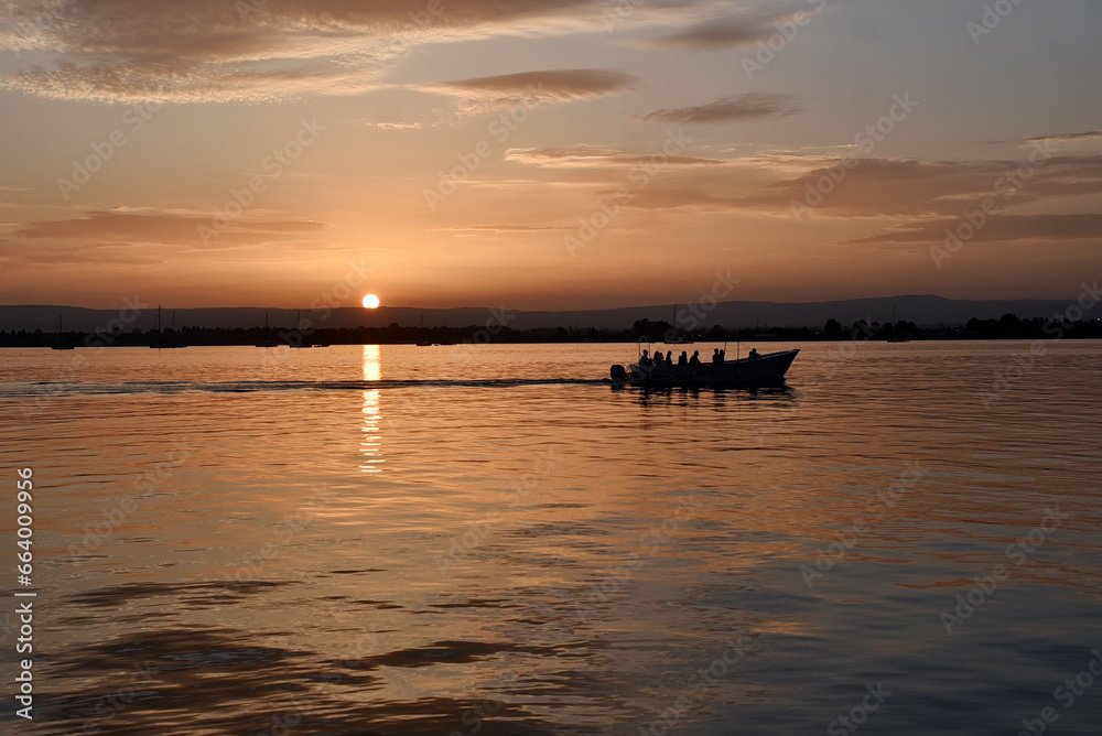 A boat floating on a sunset on a Sicilian coast from Italy 