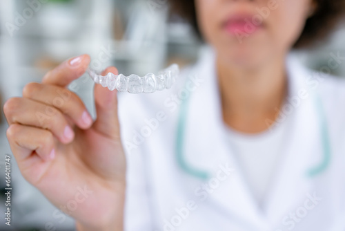 Crop of anonymous female dentist hand holding a clear dental aligner