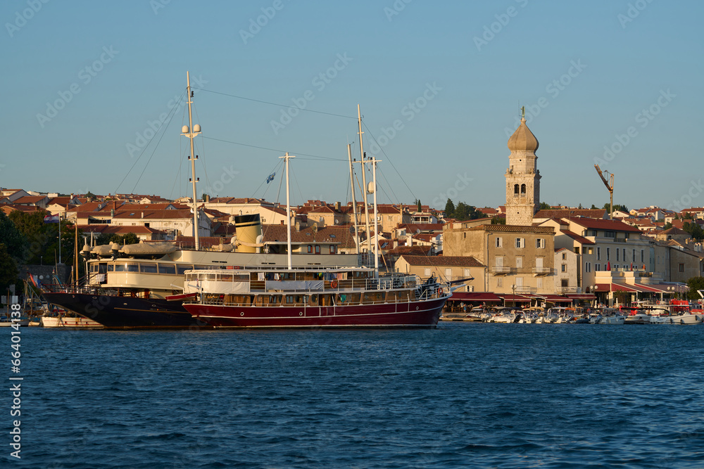 View of the harbor with a large ship and the old town of Krk in Croatia during the golden hour before sunset.