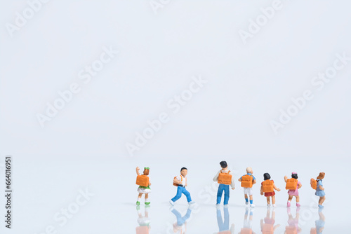 schoolchildren with schoolbags on white background, miniature figures scene, copy space
