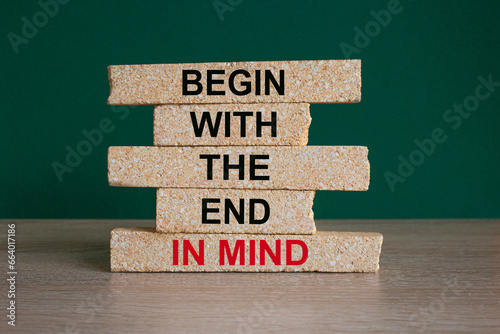Concept red words Begin with the end in mind on brick blocks. Beautiful wooden table green background. Business begin in end of mind concept. Copy space.