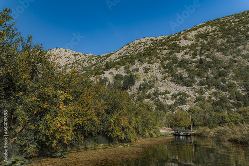 Podróż po jeziorze. Góry jezioro i łódka. Turyści na łodzi. Ludzie w łódce na jeziorze wśród gór. Ludzie i góry. Jezioro i ludzie. Wysokie góry w Chorwacji. Delta Neretwy