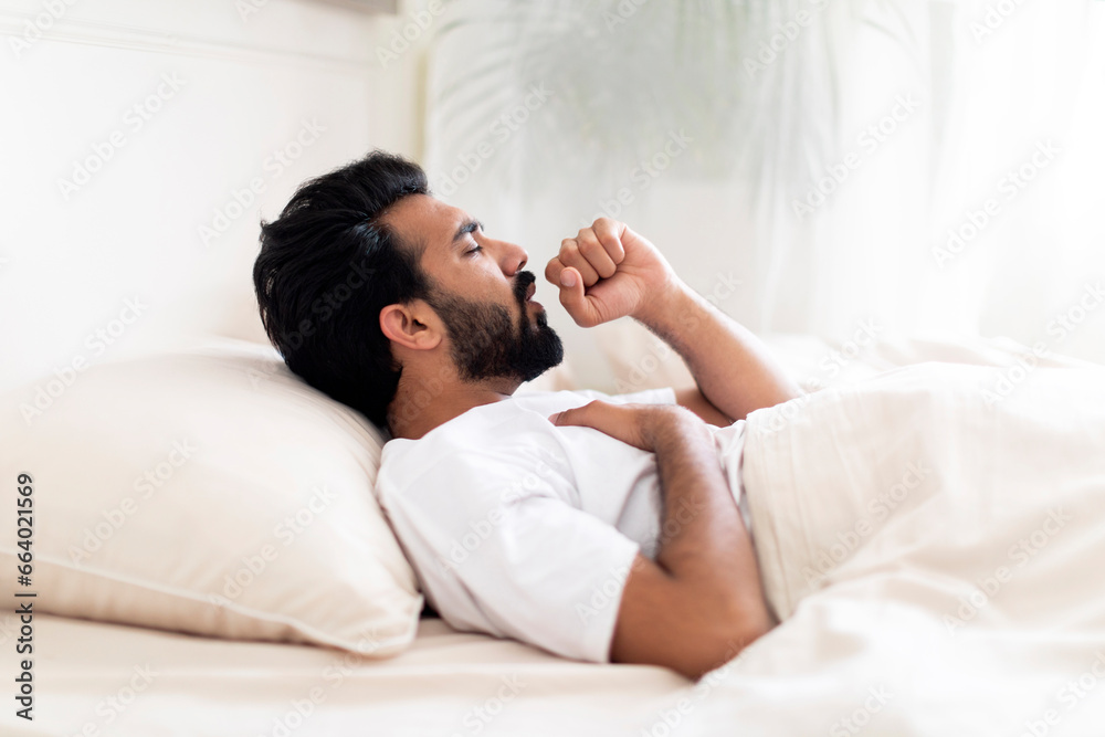 Sick Young Indian Man Coughing While Lying In Bed At Home Sick Young Indian Man Coughing While Lying In Bed At Home
