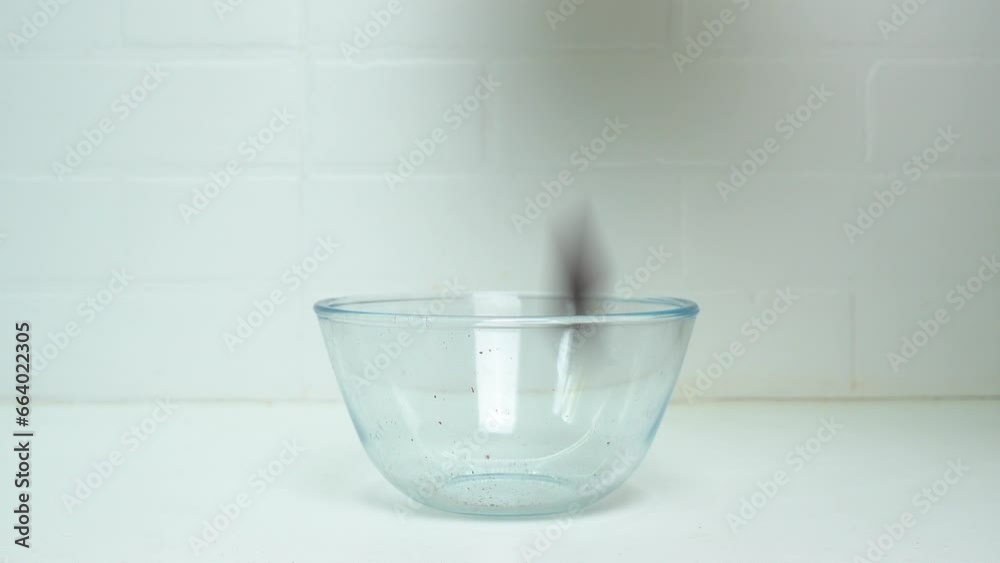 Dark chocolate pieces are poured into a glass plate on top. Side view. Dark chocolate pieces are poured into a glass plate on top. Side view.