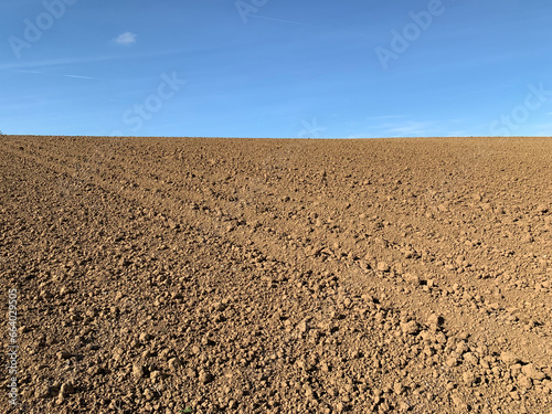 Only sky and earth on the horizon. A plowed field against a blue sky in sunny weather in Germany. State of Baden-Württemberg.