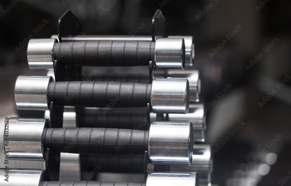Metal dumbbells on an iron stand in a sports hall, close-up on a black background. Sports concept, fat burning and Metal dumbbells on an iron stand in a sports hall, close-up on a black background. Metal dumbbells on an iron stand in a sports hall, close-up on a black background. Sports concept, fat burning and Metal dumbbells on an iron stand in a sports hall, close-up on a black background.
