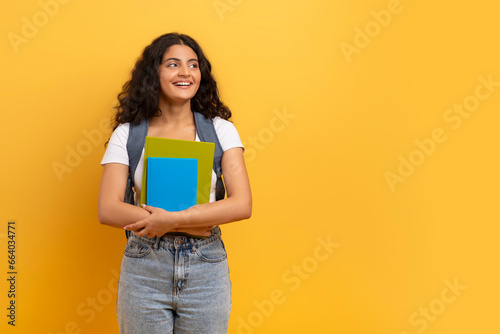 Smiling indian woman student holding notebooks looking at copy space