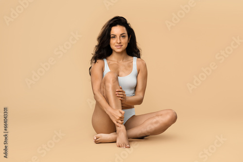 Beautiful young woman posing in underwear over beige studio background