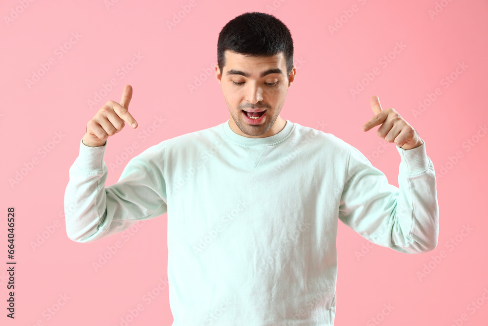 Young man pointing at something on pink background Young man pointing at something on pink background