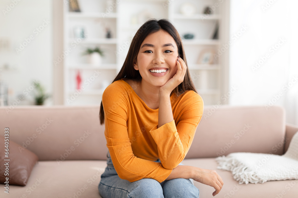 Portrait of cheerful young asian woman posing at home