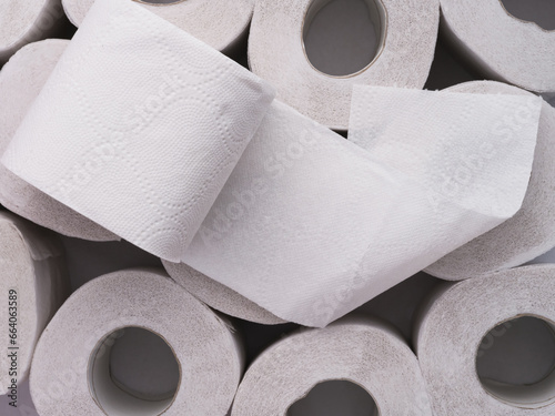 A toilet roll lying on top of heap of toilet paper rolls