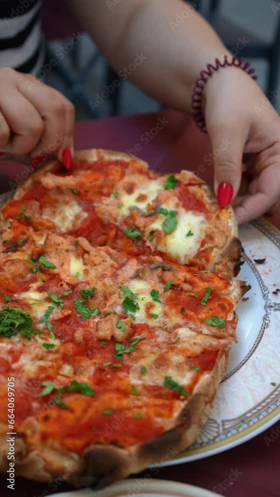 Close-up vertical cropped shot of unrecognizable woman taking slice being cut from freshly baked Margherita pizza, slice lifted, gooey mozzarella cheese stretches, capturing essence of deliciousness. Close-up vertical cropped shot of unrecognizable woman taking slice being cut from freshly baked Margherita pizza, slice lifted, gooey mozzarella cheese stretches, capturing essence of deliciousness.