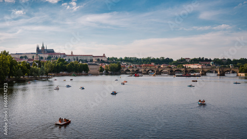 Photography View of Prague Castle and Charles Bridge in summer with boats on the Vltava Rive