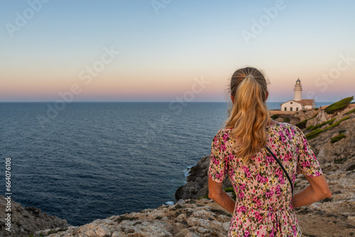 Blond Girl at the Capdepera Lighthouse with the Mediterranean Sea in the background at Cala Ratjada on Majorca Island, Spain
