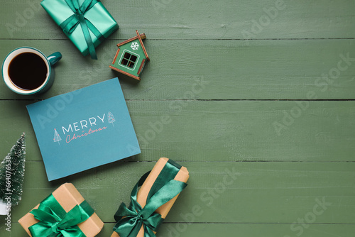 Beautiful Christmas composition with greeting card, gift boxes and cup of coffee on green wooden background